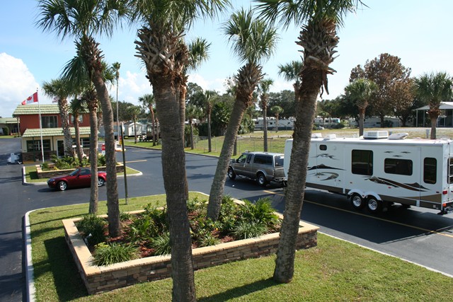 truck and rv entering campground with palm trees in front